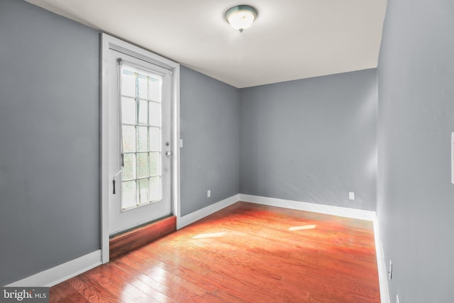 doorway to outside featuring baseboards and wood finished floors