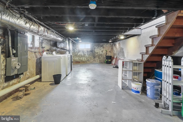 basement featuring electric panel, washing machine and clothes dryer, and stairs