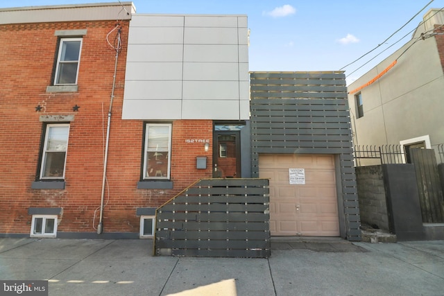 view of front of property with a garage, brick siding, and fence