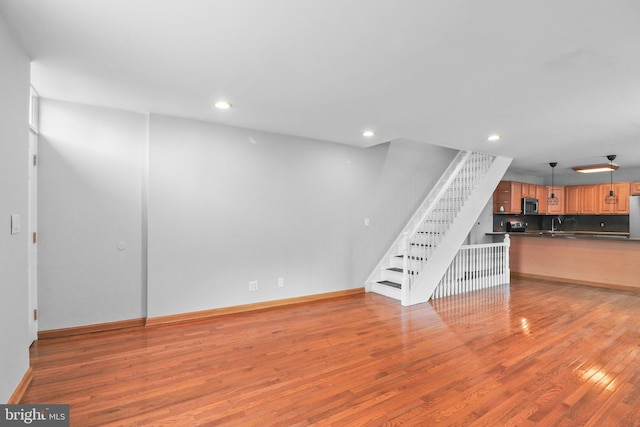 unfurnished living room with stairs, baseboards, hardwood / wood-style flooring, and recessed lighting