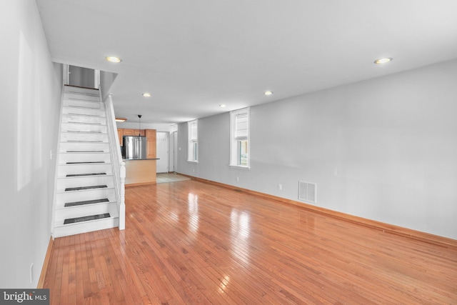 unfurnished living room featuring recessed lighting, visible vents, light wood-style flooring, and stairs