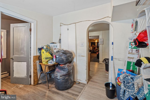 interior space featuring wood finished floors, arched walkways, and a baseboard radiator