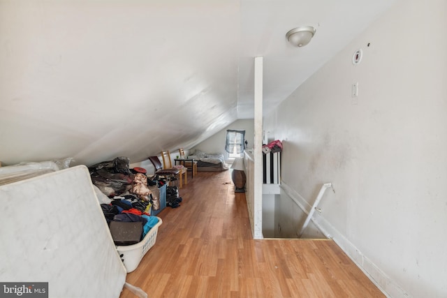 additional living space featuring baseboards, wood finished floors, and vaulted ceiling