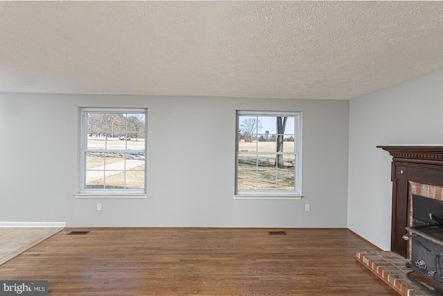 unfurnished living room with a wealth of natural light, visible vents, and wood finished floors