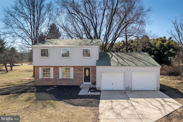 colonial-style house featuring a garage, brick siding, driveway, a chimney, and a front yard