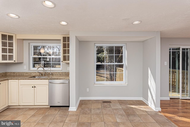 kitchen featuring visible vents, glass insert cabinets, a sink, dark stone counters, and dishwasher