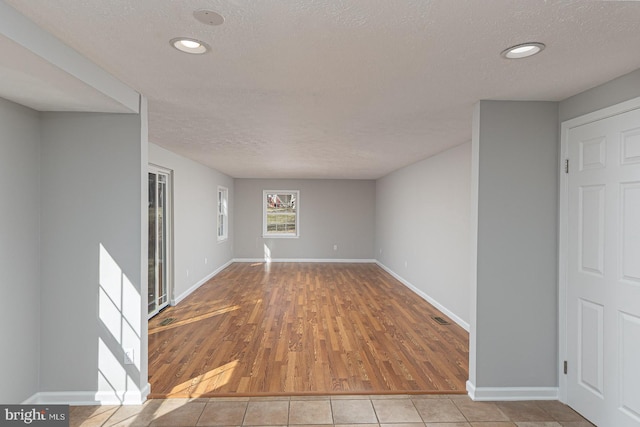 spare room featuring a textured ceiling, recessed lighting, visible vents, baseboards, and tile patterned floors