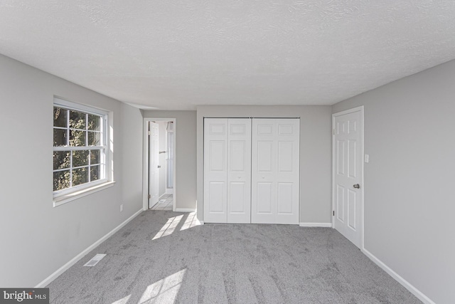 unfurnished bedroom with a closet, carpet, visible vents, and baseboards