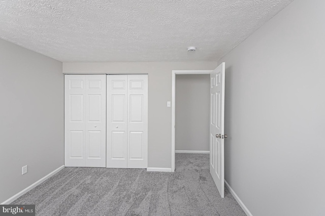 unfurnished bedroom featuring carpet, a closet, a textured ceiling, and baseboards