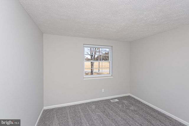 spare room featuring dark colored carpet, visible vents, a textured ceiling, and baseboards