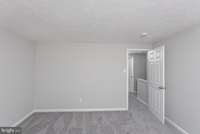 carpeted spare room with a textured ceiling and baseboards