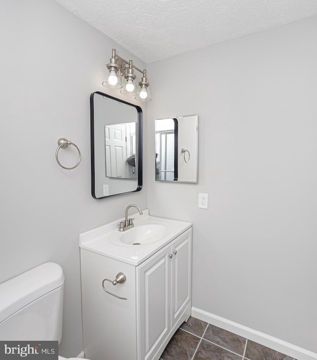 bathroom featuring a textured ceiling, toilet, vanity, baseboards, and tile patterned floors