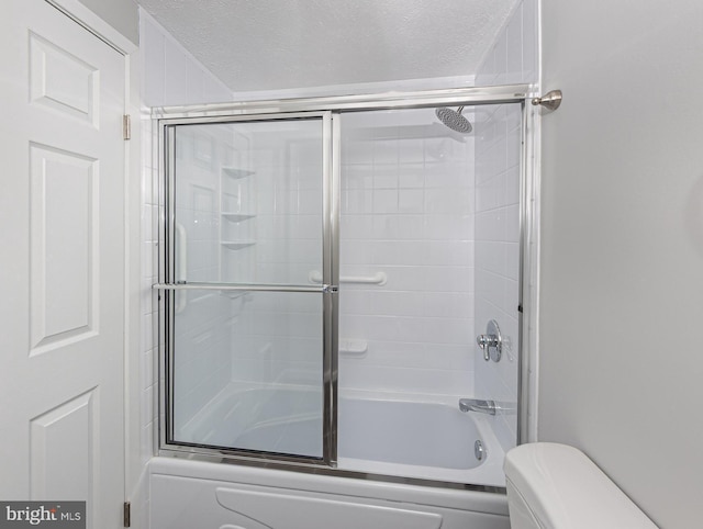 full bathroom with combined bath / shower with glass door, a textured ceiling, and toilet