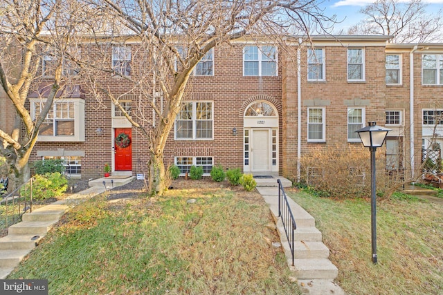 multi unit property featuring brick siding and a front lawn