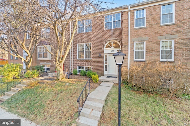 view of property featuring a front lawn and brick siding