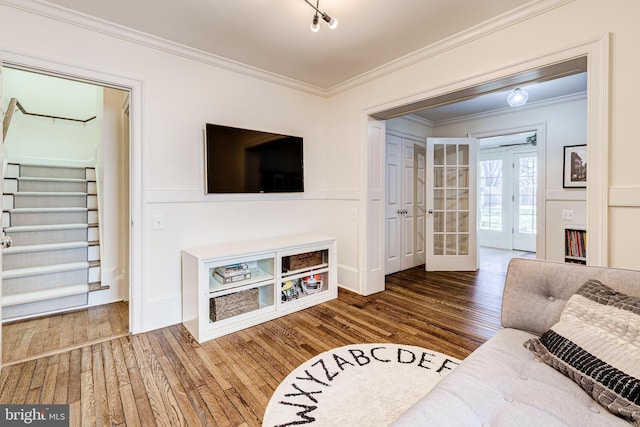 living area with french doors, crown molding, stairway, ceiling fan, and wood finished floors