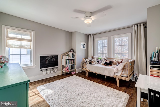 bedroom featuring multiple windows, baseboards, dark wood finished floors, and a fireplace