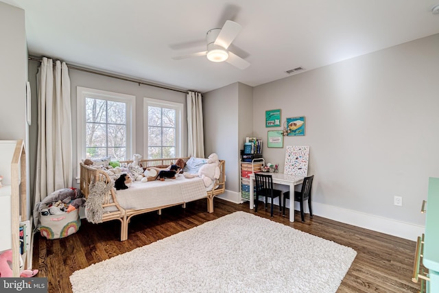 bedroom with a ceiling fan, visible vents, baseboards, and wood finished floors