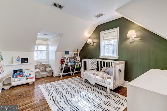 bedroom with lofted ceiling, wood finished floors, and visible vents