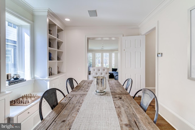 dining area featuring built in features, french doors, crown molding, wood finished floors, and baseboards