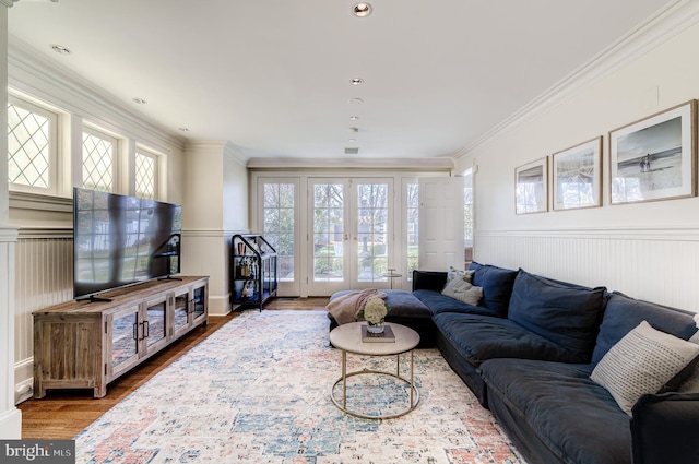 living room with a wainscoted wall, ornamental molding, wood finished floors, and french doors