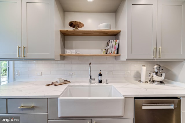 kitchen featuring light stone counters, a sink, decorative backsplash, and open shelves