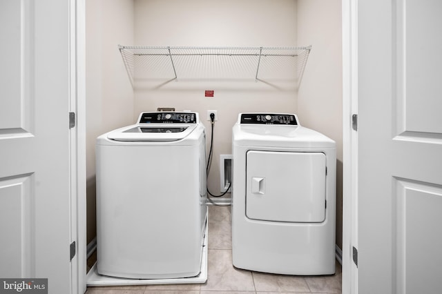 washroom with washer and dryer, laundry area, and light tile patterned floors