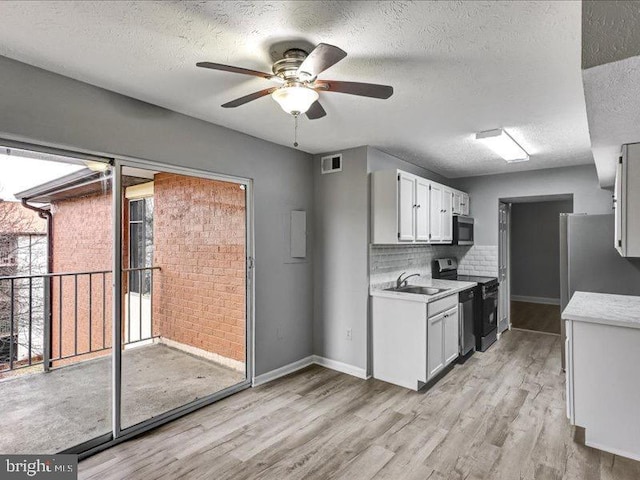 kitchen with stainless steel appliances, a sink, visible vents, light wood-style floors, and light countertops