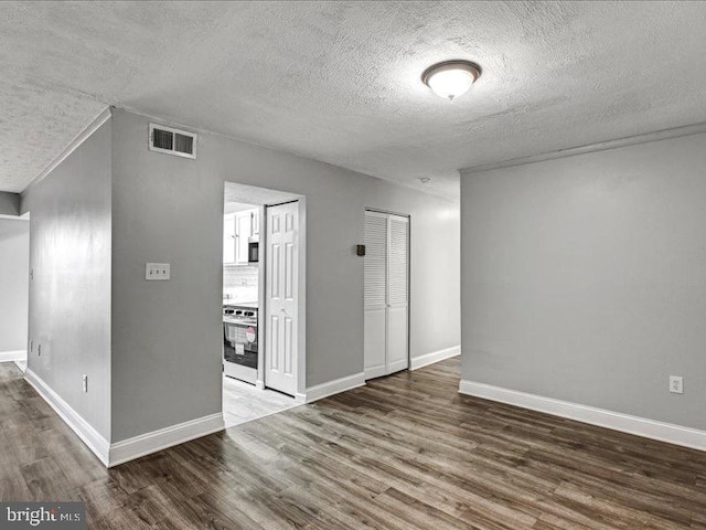 empty room with wood finished floors, visible vents, and baseboards