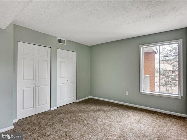 unfurnished bedroom featuring carpet floors, visible vents, and baseboards