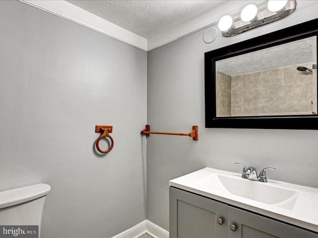 bathroom featuring a textured ceiling, vanity, toilet, and baseboards