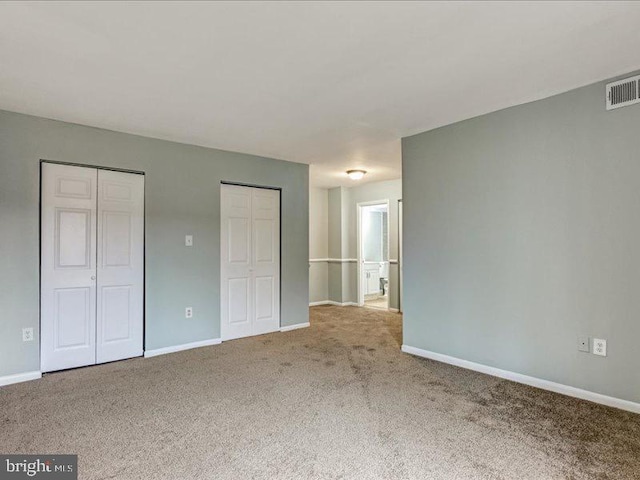 unfurnished bedroom featuring carpet floors, baseboards, and multiple closets