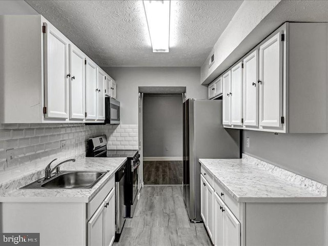 kitchen with appliances with stainless steel finishes, light wood-type flooring, light countertops, and a sink