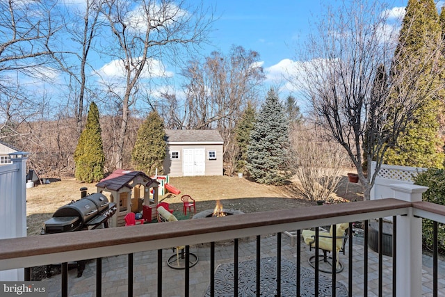 exterior space featuring a playground, a storage shed, a grill, an outdoor structure, and a fire pit