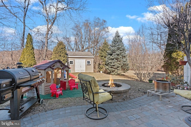 view of patio featuring a fire pit, grilling area, an outbuilding, a shed, and a playground