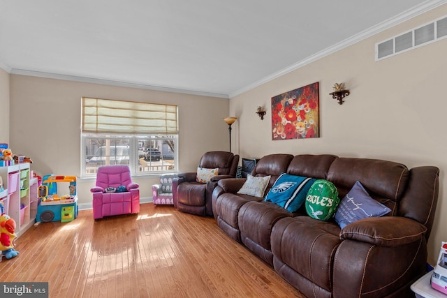 living room with ornamental molding, wood-type flooring, visible vents, and baseboards