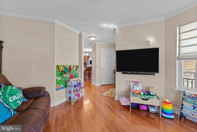 playroom with ornamental molding, a chandelier, baseboards, and wood finished floors