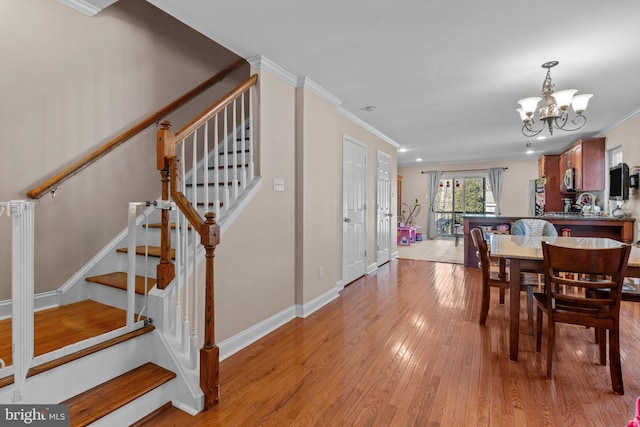 dining area with a notable chandelier, crown molding, stairway, light wood-style floors, and baseboards