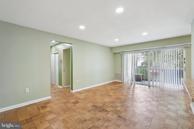 empty room featuring a barn door, recessed lighting, visible vents, and baseboards