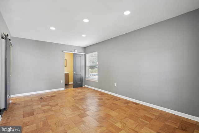 spare room featuring recessed lighting, baseboards, and a barn door