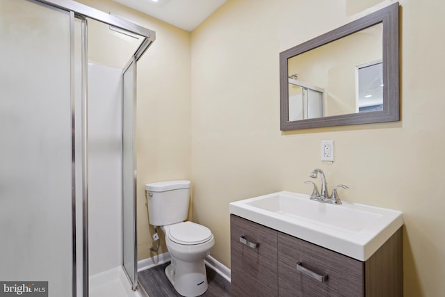 bathroom featuring toilet, a stall shower, baseboards, and vanity