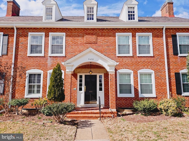 view of front of property featuring brick siding and a chimney