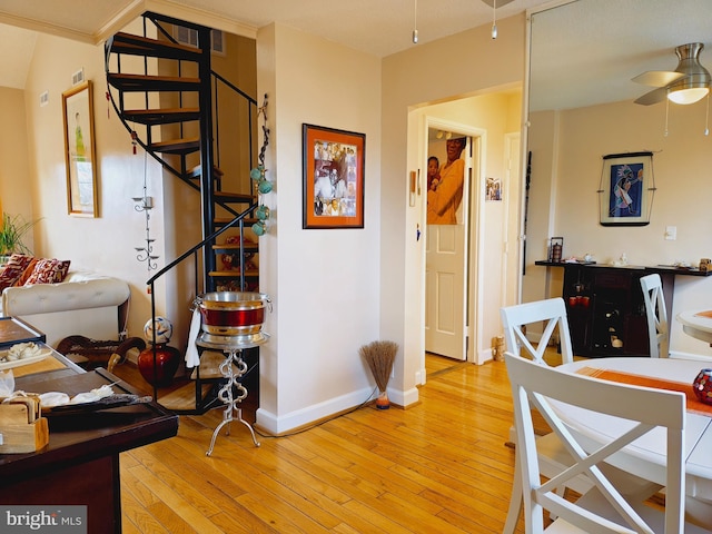 dining room with light wood finished floors, stairs, baseboards, and a ceiling fan