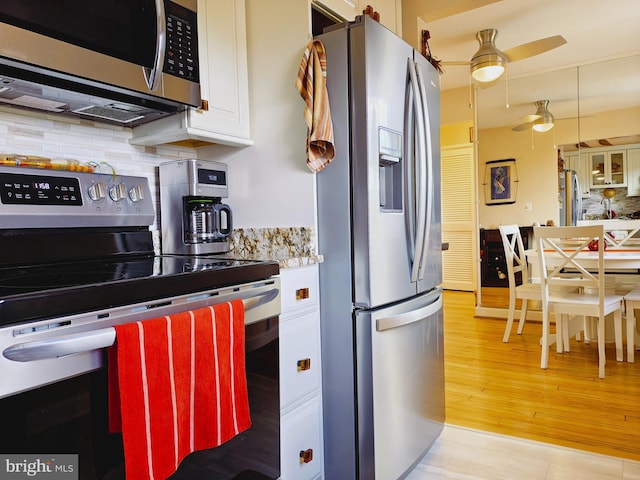 kitchen featuring tasteful backsplash, light wood-style flooring, appliances with stainless steel finishes, white cabinetry, and ceiling fan