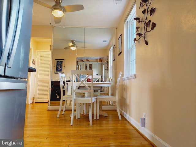 dining space with visible vents, hardwood / wood-style floors, a ceiling fan, and baseboards