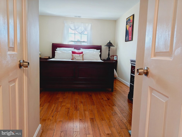 bedroom featuring baseboards, visible vents, and hardwood / wood-style floors