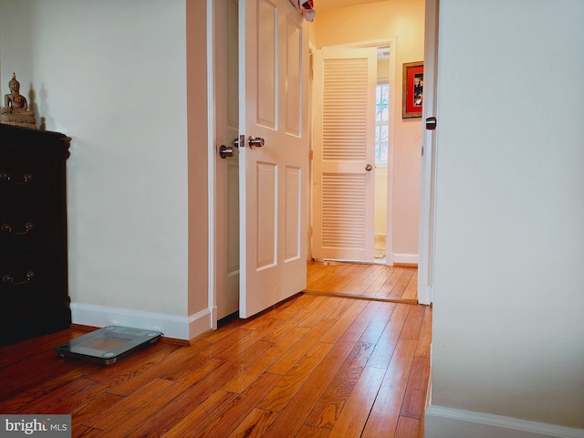 hallway with light wood-type flooring and baseboards