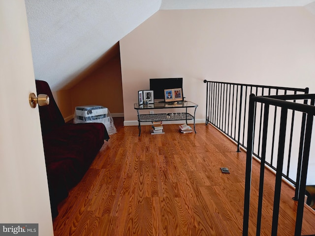 living area featuring lofted ceiling, wood finished floors, and baseboards