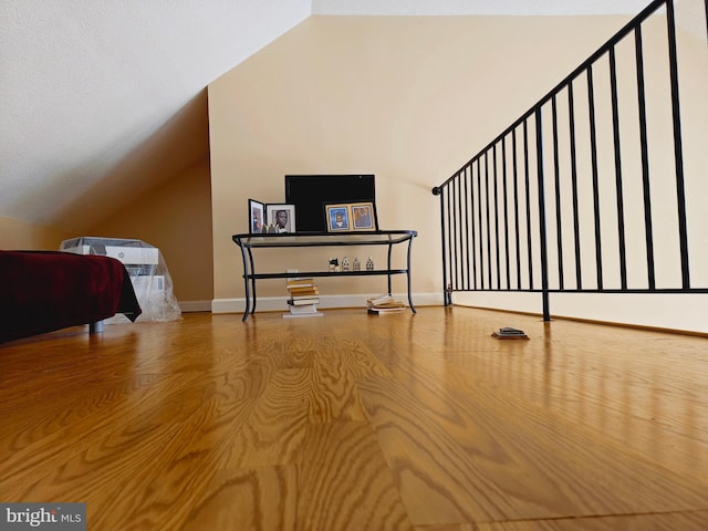 additional living space with vaulted ceiling, baseboards, and wood finished floors