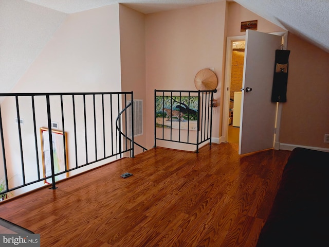 interior space with lofted ceiling, visible vents, wood finished floors, and an upstairs landing